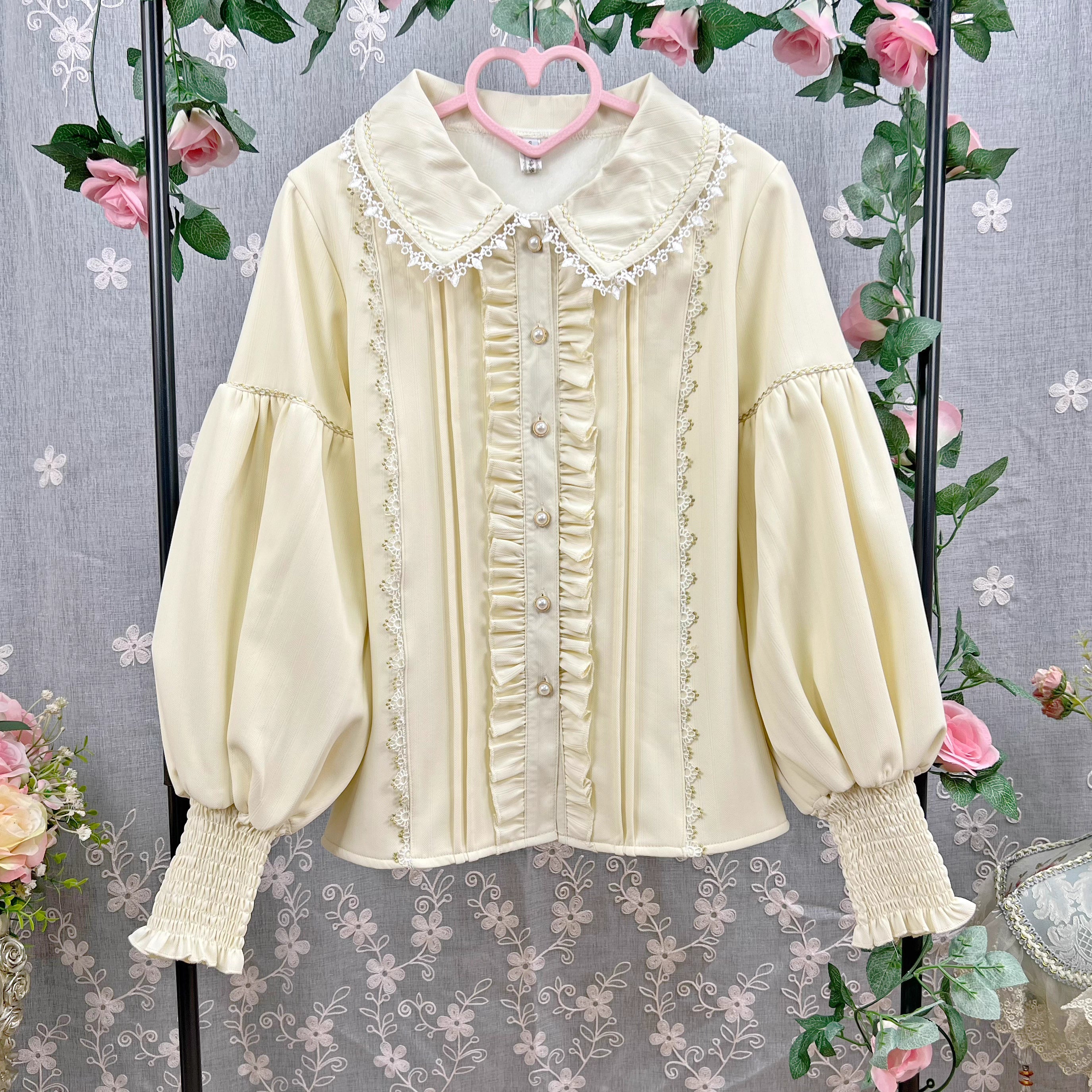 This Lolita blouse combines vintage CLA-inspired elegance with court-style sophistication. Featuring a delicate doll collar and refined tailoring, it adds a charming, graceful touch to any Lolita outfit. Available in Beige, Black, and White, this blouse is perfect as a layering piece under jumpers, dresses, or worn on its own for daily wear and tea parties.