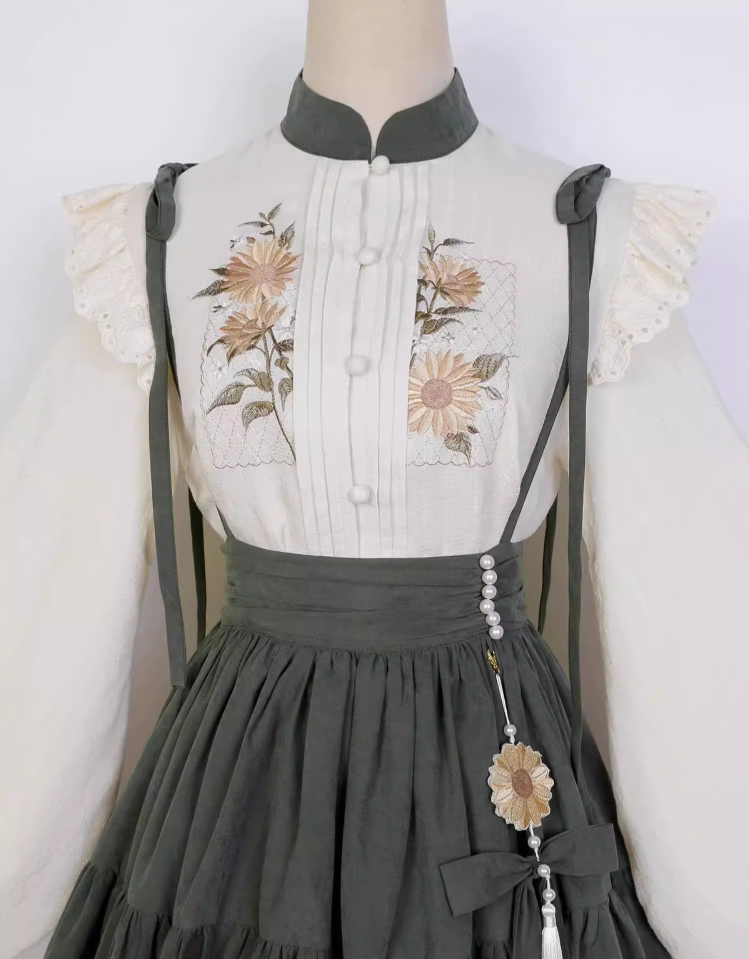 This Green Sunflower Embroidery Lolita Set blends the elegance of Hanfu-inspired details with the sweetness of classic Lolita fashion. The delicate sunflower embroidery brings a fresh pastoral charm, while the layered JSK and long-sleeve blouse create a refined silhouette. Designed for comfort and beauty, it is perfect for spring and autumn wear. Whether for tea parties, garden walks, or seasonal gatherings, this set captures a graceful harmony of tradition and modern Lolita style.