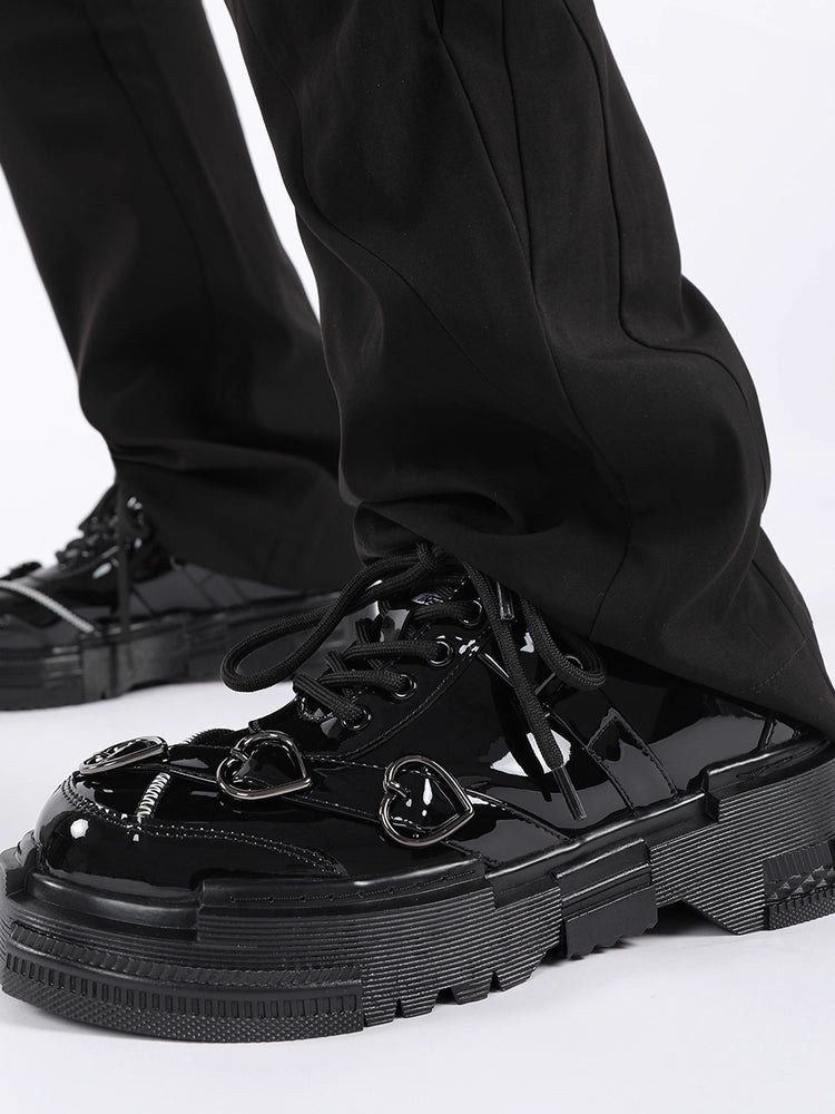 Black glossy sneakers worn with black pants on a white background