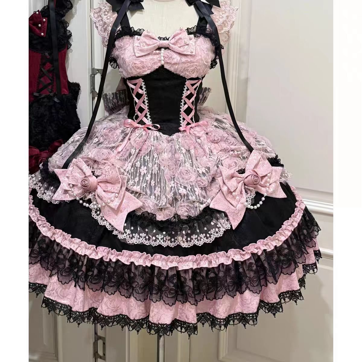 The Black Pink Ballet Lolita JSK Dress is crafted to express elegance with a playful, dance-inspired charm. Featuring a sleeveless cut, layered ruffles, and delicate lace, it creates a graceful silhouette reminiscent of a ballerina’s costume. The lace-up detail ensures both beauty and flexibility, while bow accents add sweetness to the design. With its striking black and pink contrast, this dress is perfect for tea parties, performances, or special Lolita occasions.
