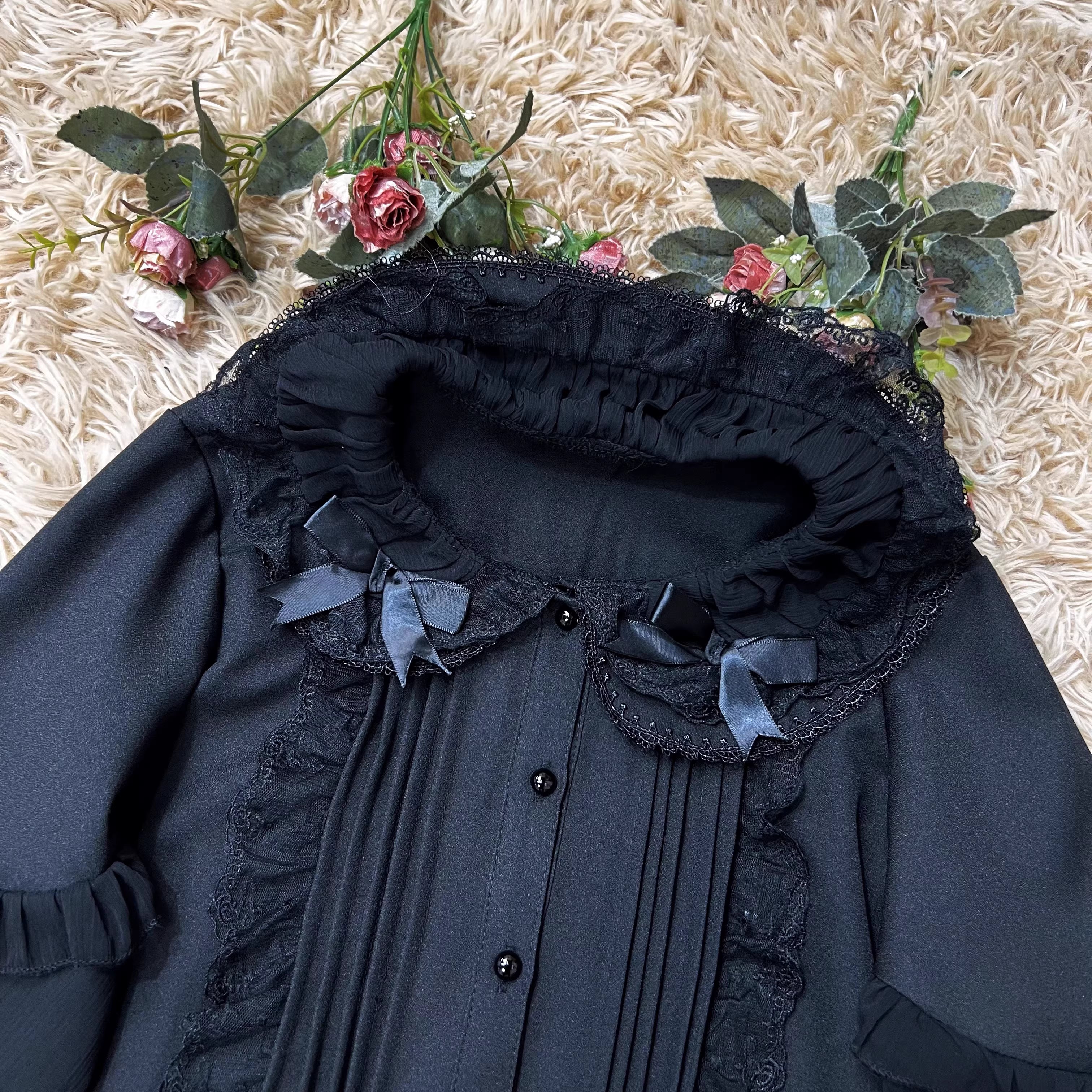 This classic Lolita blouse features a delicate Peter Pan collar and soft bishop sleeves with subtle puff detailing. Rendered in timeless black and white, its accordion pleats and bloom-inspired ruffles add vintage charm to any coordination. The lightweight fabric and tailored fit make it ideal for layering under jumpers or dresses, blending doll-like sweetness with elegant Gothic sophistication for daily wear or special occasions.