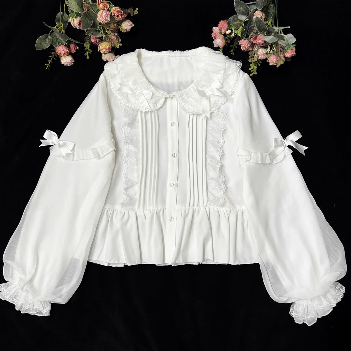 This classic Lolita blouse features a delicate Peter Pan collar and soft bishop sleeves with subtle puff detailing. Rendered in timeless black and white, its accordion pleats and bloom-inspired ruffles add vintage charm to any coordination. The lightweight fabric and tailored fit make it ideal for layering under jumpers or dresses, blending doll-like sweetness with elegant Gothic sophistication for daily wear or special occasions.