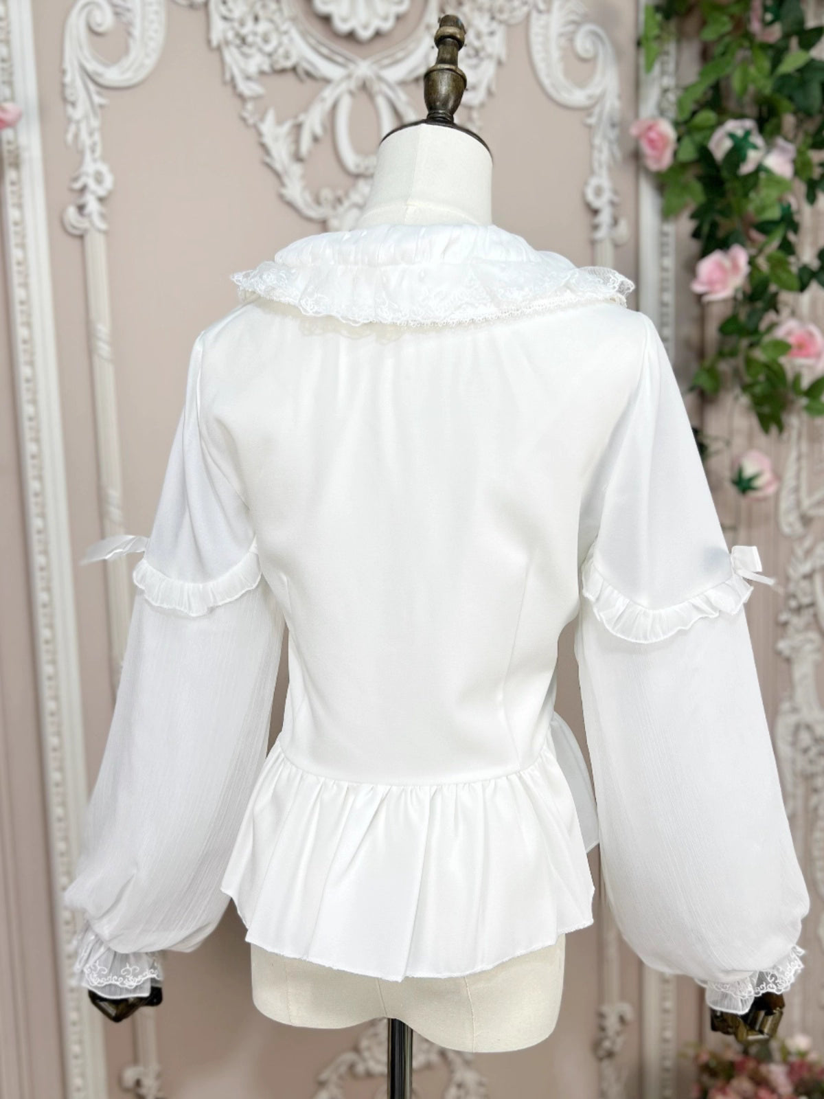 This classic Lolita blouse features a delicate Peter Pan collar and soft bishop sleeves with subtle puff detailing. Rendered in timeless black and white, its accordion pleats and bloom-inspired ruffles add vintage charm to any coordination. The lightweight fabric and tailored fit make it ideal for layering under jumpers or dresses, blending doll-like sweetness with elegant Gothic sophistication for daily wear or special occasions.