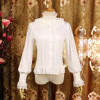 This vintage-inspired blouse features an elegant stand collar and delicate ruffled sleeves crafted from lightweight chiffon. The tailored fit and button-front design create a flattering silhouette, perfect for layering under jumpers or dresses. Its timeless elegance blends retro charm with Lolita sophistication, making it ideal for both classic and sweet coordinates.