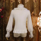 This vintage-inspired blouse features an elegant stand collar and delicate ruffled sleeves crafted from lightweight chiffon. The tailored fit and button-front design create a flattering silhouette, perfect for layering under jumpers or dresses. Its timeless elegance blends retro charm with Lolita sophistication, making it ideal for both classic and sweet coordinates.