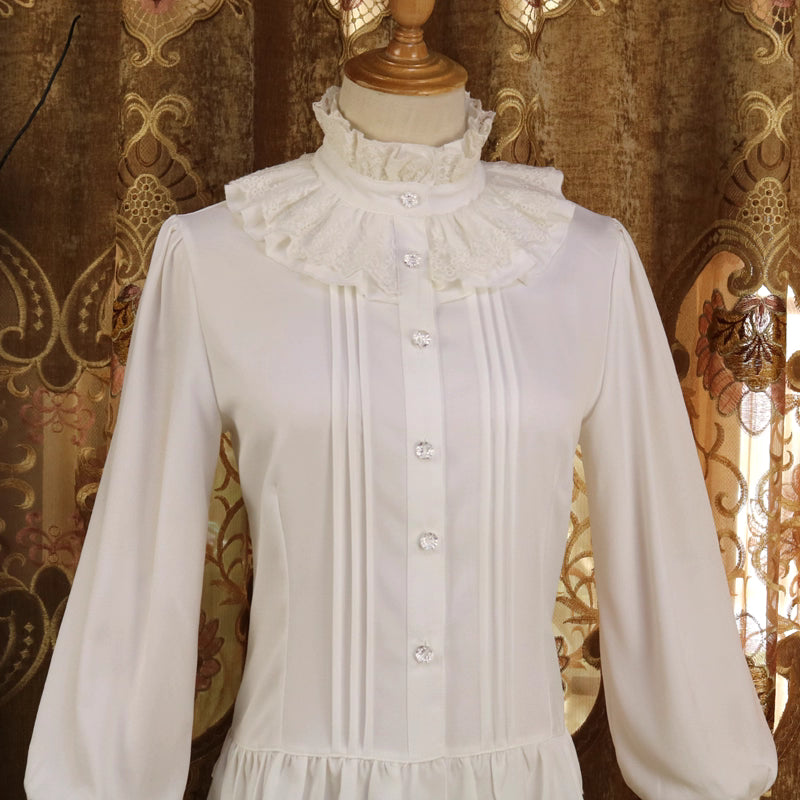 This vintage-inspired blouse features an elegant stand collar and delicate ruffled sleeves crafted from lightweight chiffon. The tailored fit and button-front design create a flattering silhouette, perfect for layering under jumpers or dresses. Its timeless elegance blends retro charm with Lolita sophistication, making it ideal for both classic and sweet coordinates.