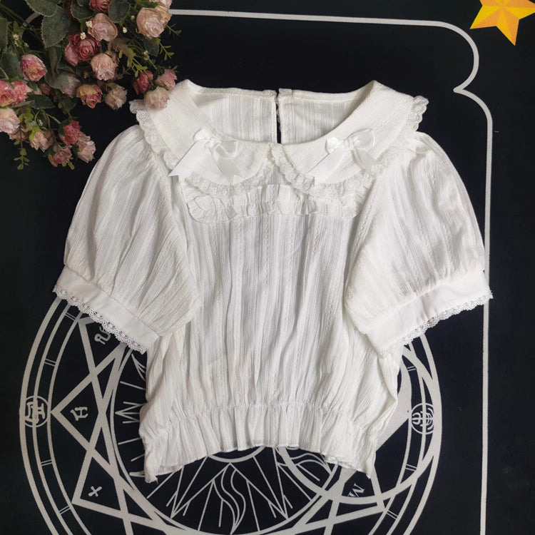 Crafted from breathable cotton, this charming short-sleeve blouse features a classic Peter Pan collar and delicate bow tie. The playful plaid pattern in multiple colors offers versatile styling for both Lolita and JK fashion. Its lightweight comfort and sweet design make it ideal for daily wear, effortlessly pairing with jumpers, skirts, or dresses for a fresh, youthful look.
