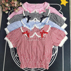 Crafted from breathable cotton, this charming short-sleeve blouse features a classic Peter Pan collar and delicate bow tie. The playful plaid pattern in multiple colors offers versatile styling for both Lolita and JK fashion. Its lightweight comfort and sweet design make it ideal for daily wear, effortlessly pairing with jumpers, skirts, or dresses for a fresh, youthful look.