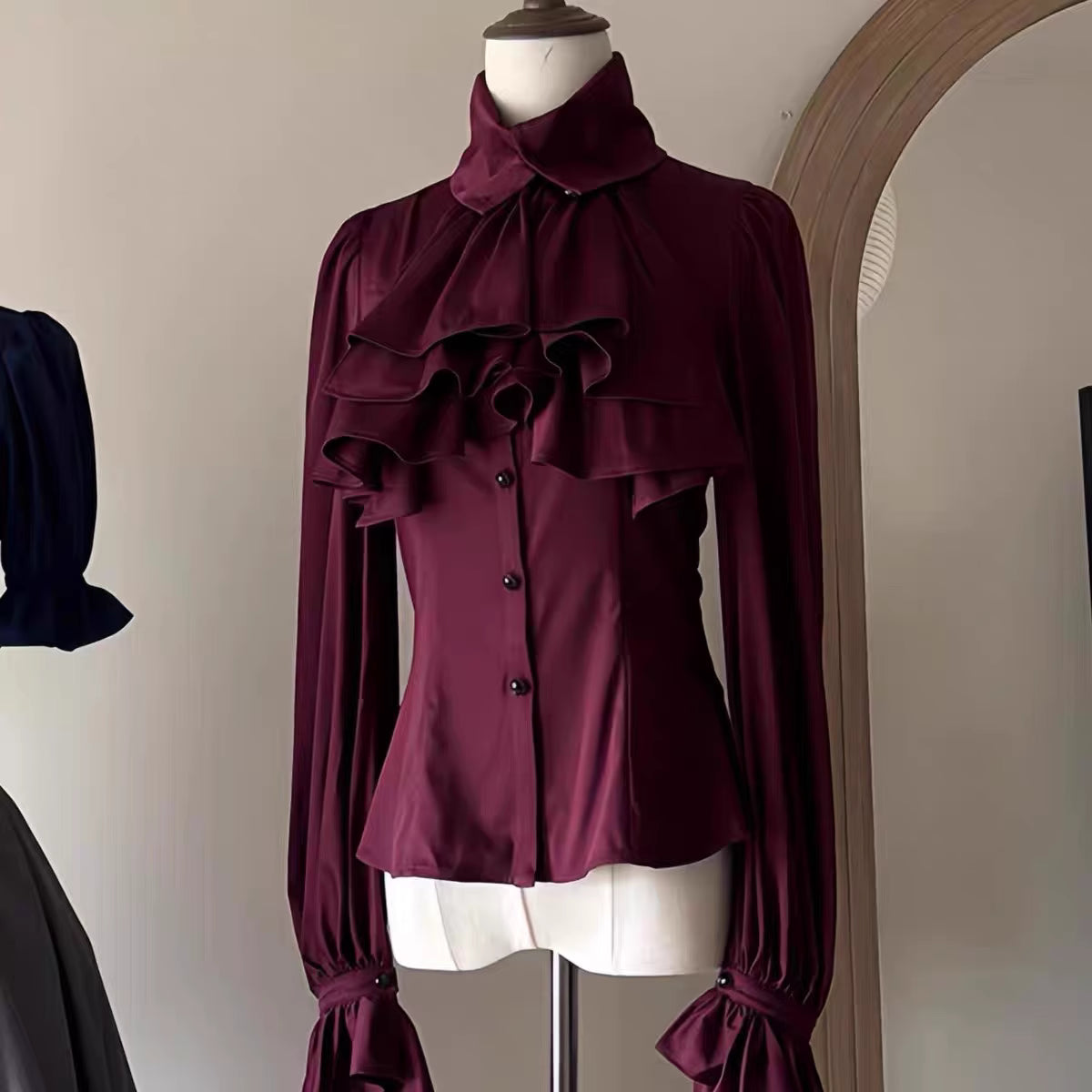 Step into Victorian elegance with this Gothic Lolita blouse. Delicate ruffles frame the Peter Pan collar and cascade down the front, while billowy bishop sleeves add dramatic flair. Crafted from premium opaque fabric, this retro-inspired top features intricate lace detailing and a tailored fit. Available in classic black, vampy red, and pristine white, it serves as the perfect layering piece for JSKs or a statement standalone top. Embrace dark romance with this timeless essential.
