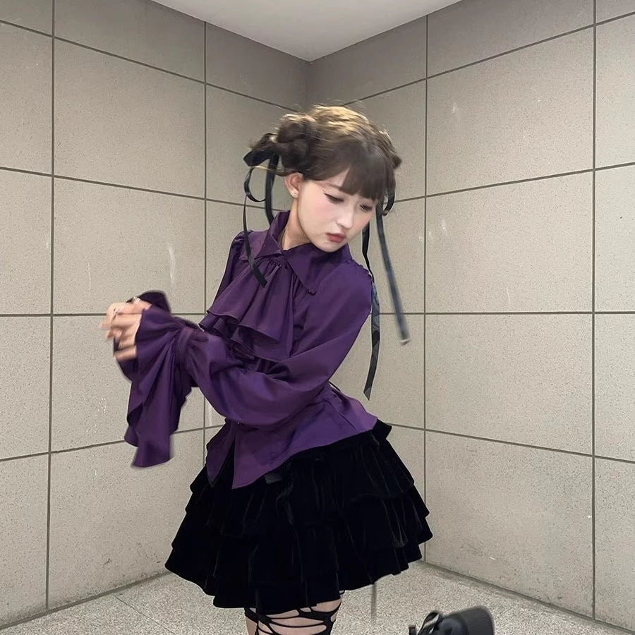 Step into Victorian elegance with this Gothic Lolita blouse. Delicate ruffles frame the Peter Pan collar and cascade down the front, while billowy bishop sleeves add dramatic flair. Crafted from premium opaque fabric, this retro-inspired top features intricate lace detailing and a tailored fit. Available in classic black, vampy red, and pristine white, it serves as the perfect layering piece for JSKs or a statement standalone top. Embrace dark romance with this timeless essential.