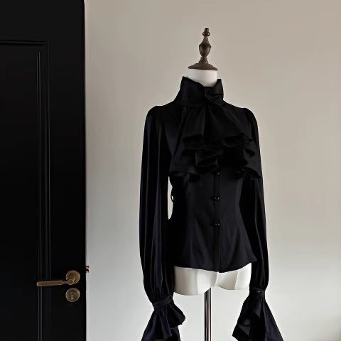 Step into Victorian elegance with this Gothic Lolita blouse. Delicate ruffles frame the Peter Pan collar and cascade down the front, while billowy bishop sleeves add dramatic flair. Crafted from premium opaque fabric, this retro-inspired top features intricate lace detailing and a tailored fit. Available in classic black, vampy red, and pristine white, it serves as the perfect layering piece for JSKs or a statement standalone top. Embrace dark romance with this timeless essential.