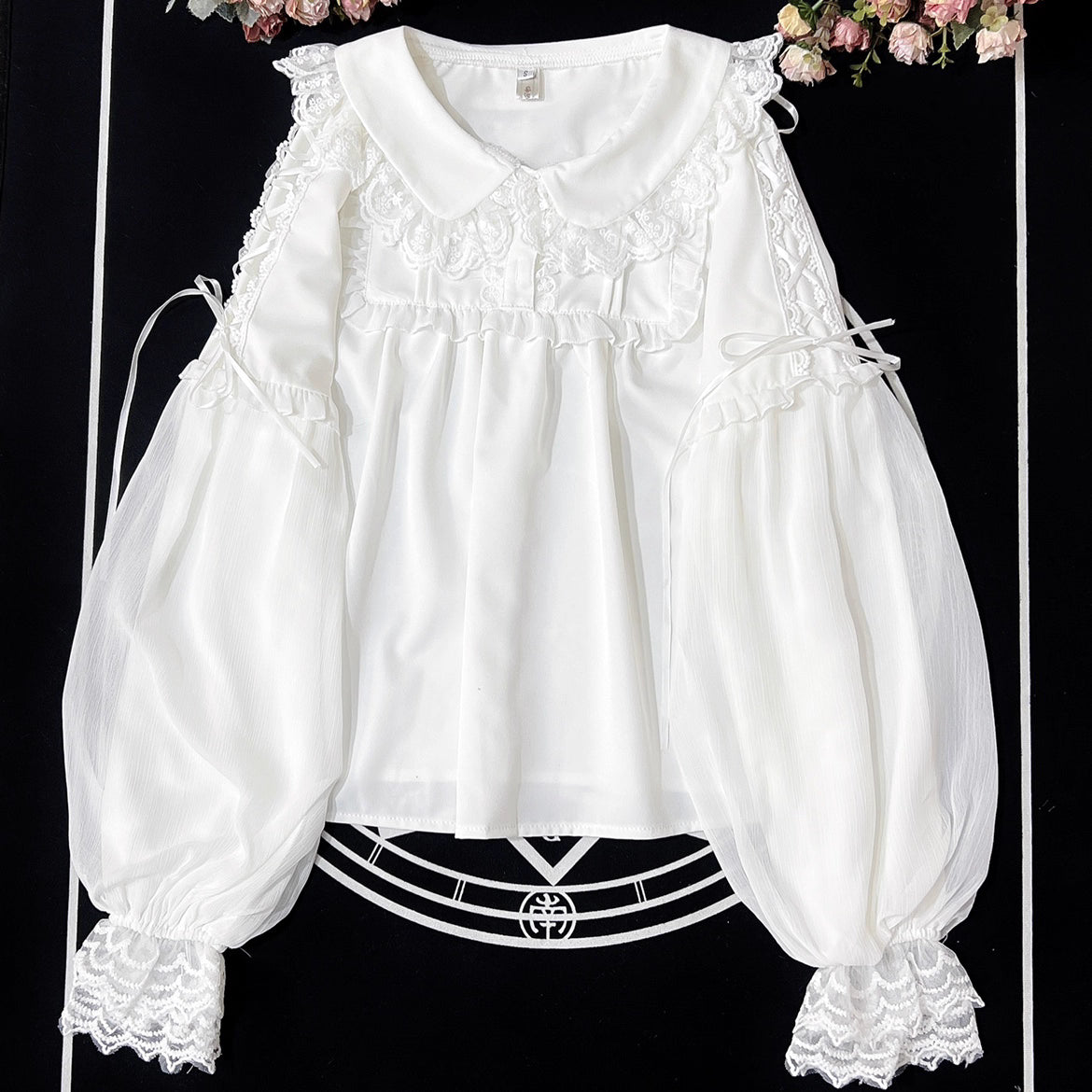 Embodying the freshness of spring, this delicate blouse features a lace-trimmed doll collar adorned with satin ribbons and soft bishop sleeves. The lightweight fabric and sweet design make it perfect for layering under jumpers or dresses. Its romantic details capture a whimsical, youthful charm, ideal for creating enchanting coordinations that blend vintage elegance with modern Lolita sweetness.