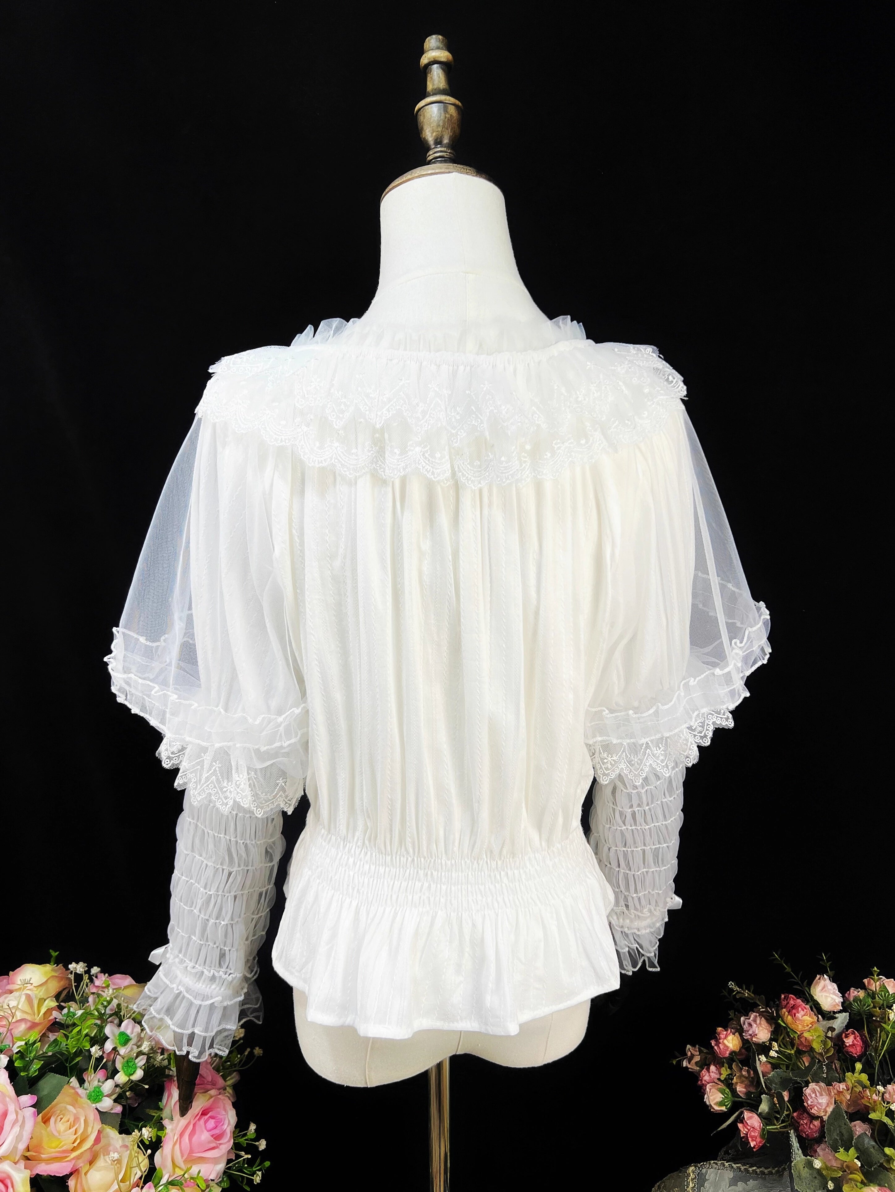 This retro-inspired blouse blends soft cotton with delicate mesh panels for textured elegance. The round neckline and relaxed fit offer timeless comfort, while subtle vintage details create a versatile layering piece. Perfect under jumpers or dresses, it effortlessly bridges classic and sweet Lolita styles with understated sophistication.