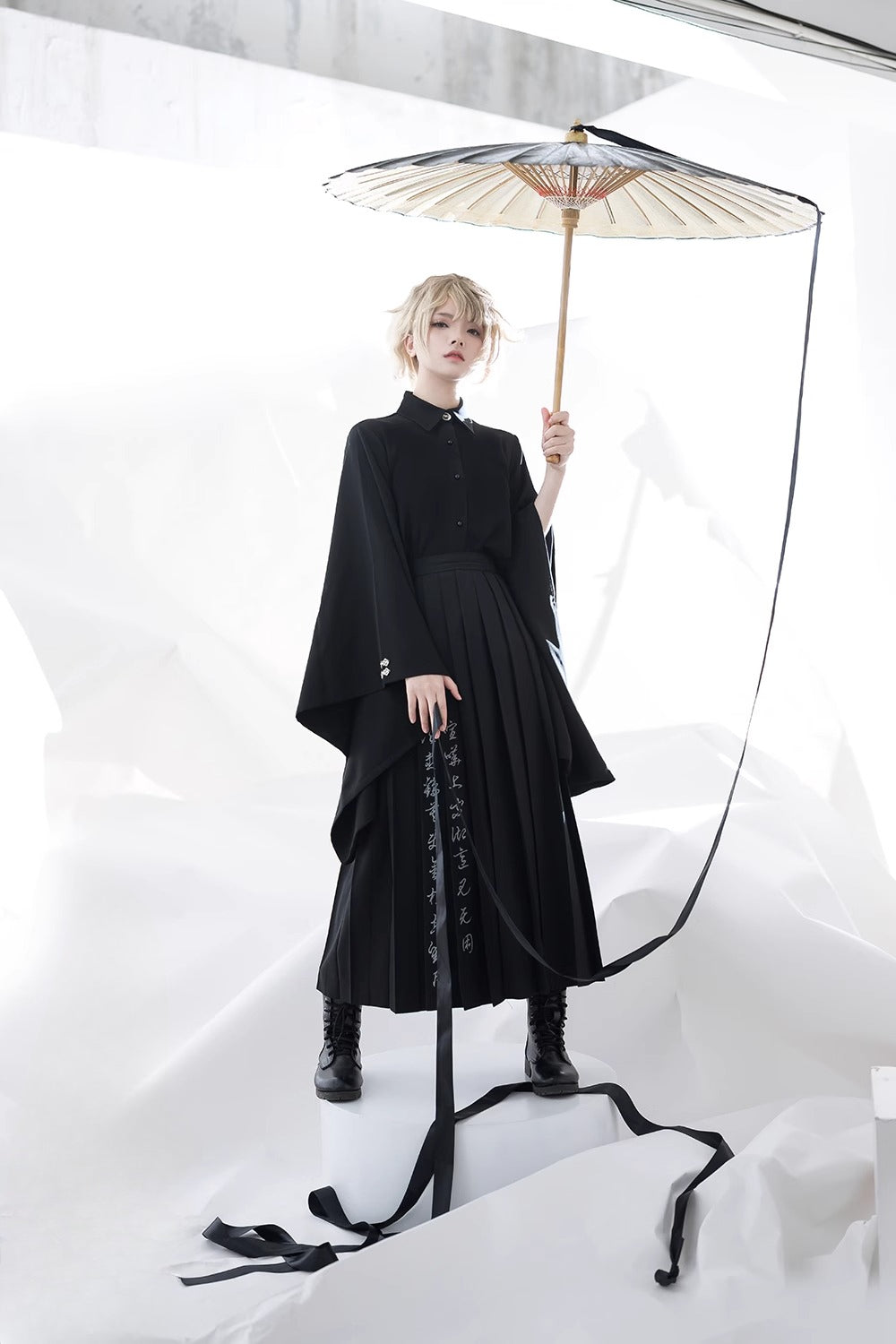 Inspired by Tang dynasty aesthetics, this top reimagines classical elegance with dramatic pointed collars and flowing wide sleeves. The luxurious black fabric serves as a canvas for subtle embroidered pomegranate motifs—symbolizing prosperity and unity. Lightweight yet structured, it layers seamlessly under modern outerwear, blending historical narrative with wearable artistry for a timeless statement of cultural fusion.