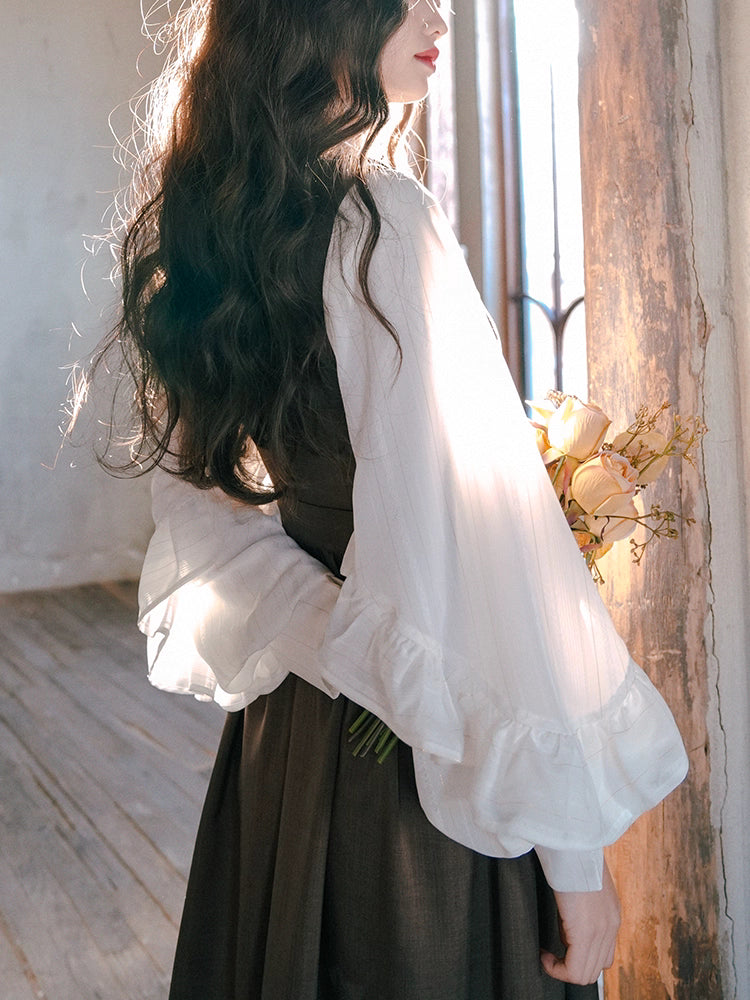 Inspired by the opulent elegance of the French court, this blouse is a masterpiece of romantic detail. Crafted in a subtly shimmering fabric, it features dramatic puff sleeves and delicate ruffled accents. The adjustable tie-front closure allows for a customizable fit, blending historical grandeur with modern wearability. This piece is designed for those who wish to infuse their everyday style with a touch of aristocratic fantasy and timeless grace.