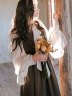 Inspired by the opulent elegance of the French court, this blouse is a masterpiece of romantic detail. Crafted in a subtly shimmering fabric, it features dramatic puff sleeves and delicate ruffled accents. The adjustable tie-front closure allows for a customizable fit, blending historical grandeur with modern wearability. This piece is designed for those who wish to infuse their everyday style with a touch of aristocratic fantasy and timeless grace.