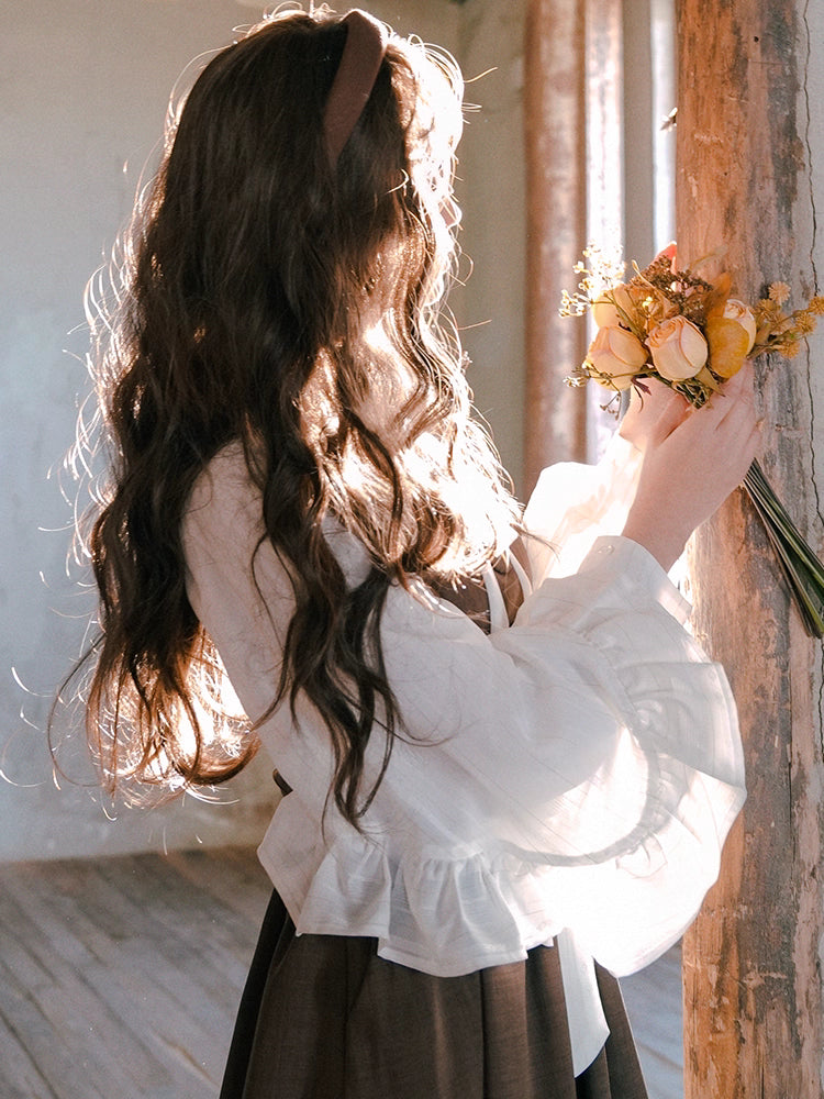 Inspired by the opulent elegance of the French court, this blouse is a masterpiece of romantic detail. Crafted in a subtly shimmering fabric, it features dramatic puff sleeves and delicate ruffled accents. The adjustable tie-front closure allows for a customizable fit, blending historical grandeur with modern wearability. This piece is designed for those who wish to infuse their everyday style with a touch of aristocratic fantasy and timeless grace.