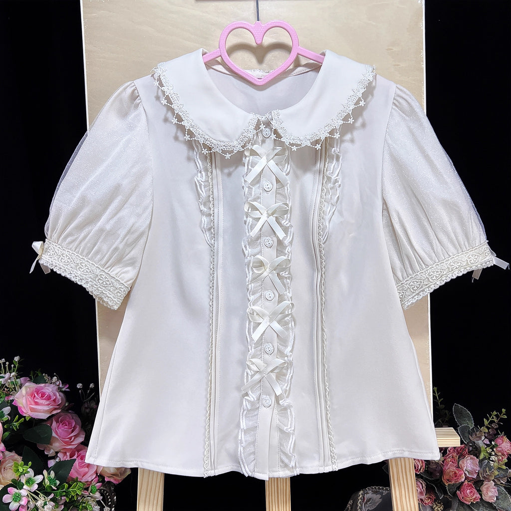 Inspired by moonlit summer nights, this delicate blouse features a classic Peter Pan collar and soft short sleeves. Crafted in pure white, its lightweight fabric and sweet design offer effortless versatility for daily wear. The subtle elegance captures a dreamy, youthful charm, perfect for pairing with summer skirts or jumpers. This piece embodies romantic simplicity, blending timeless Lolita aesthetics with modern comfort for enchanting warm-weather coordinations.