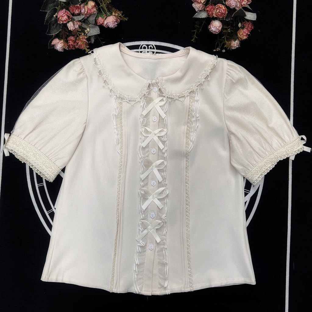 Inspired by moonlit summer nights, this delicate blouse features a classic Peter Pan collar and soft short sleeves. Crafted in pure white, its lightweight fabric and sweet design offer effortless versatility for daily wear. The subtle elegance captures a dreamy, youthful charm, perfect for pairing with summer skirts or jumpers. This piece embodies romantic simplicity, blending timeless Lolita aesthetics with modern comfort for enchanting warm-weather coordinations.