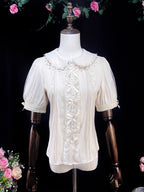 Inspired by moonlit summer nights, this delicate blouse features a classic Peter Pan collar and soft short sleeves. Crafted in pure white, its lightweight fabric and sweet design offer effortless versatility for daily wear. The subtle elegance captures a dreamy, youthful charm, perfect for pairing with summer skirts or jumpers. This piece embodies romantic simplicity, blending timeless Lolita aesthetics with modern comfort for enchanting warm-weather coordinations.