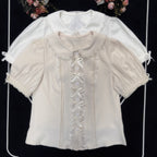 Inspired by moonlit summer nights, this delicate blouse features a classic Peter Pan collar and soft short sleeves. Crafted in pure white, its lightweight fabric and sweet design offer effortless versatility for daily wear. The subtle elegance captures a dreamy, youthful charm, perfect for pairing with summer skirts or jumpers. This piece embodies romantic simplicity, blending timeless Lolita aesthetics with modern comfort for enchanting warm-weather coordinations.