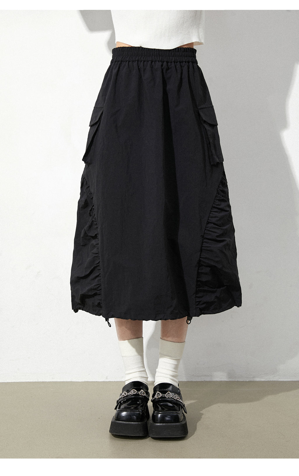 This skirt blends edgy charm with playful sweetness through its functional drawstring detail and sharp A-line silhouette. The adjustable waist and strategic pleating create a flattering, customized fit. Designed in versatile black, it balances minimalist structure with youthful rebellion, offering a statement piece that effortlessly transitions from casual daytime wear to bold nighttime street style.