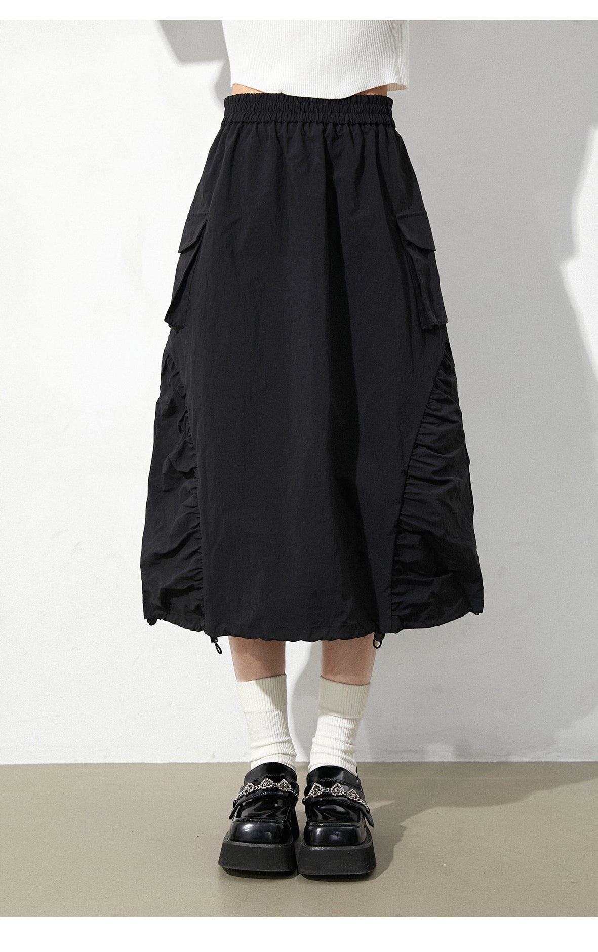 This skirt blends edgy charm with playful sweetness through its functional drawstring detail and sharp A-line silhouette. The adjustable waist and strategic pleating create a flattering, customized fit. Designed in versatile black, it balances minimalist structure with youthful rebellion, offering a statement piece that effortlessly transitions from casual daytime wear to bold nighttime street style.