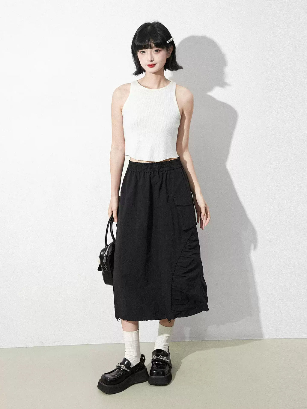 This skirt blends edgy charm with playful sweetness through its functional drawstring detail and sharp A-line silhouette. The adjustable waist and strategic pleating create a flattering, customized fit. Designed in versatile black, it balances minimalist structure with youthful rebellion, offering a statement piece that effortlessly transitions from casual daytime wear to bold nighttime street style.