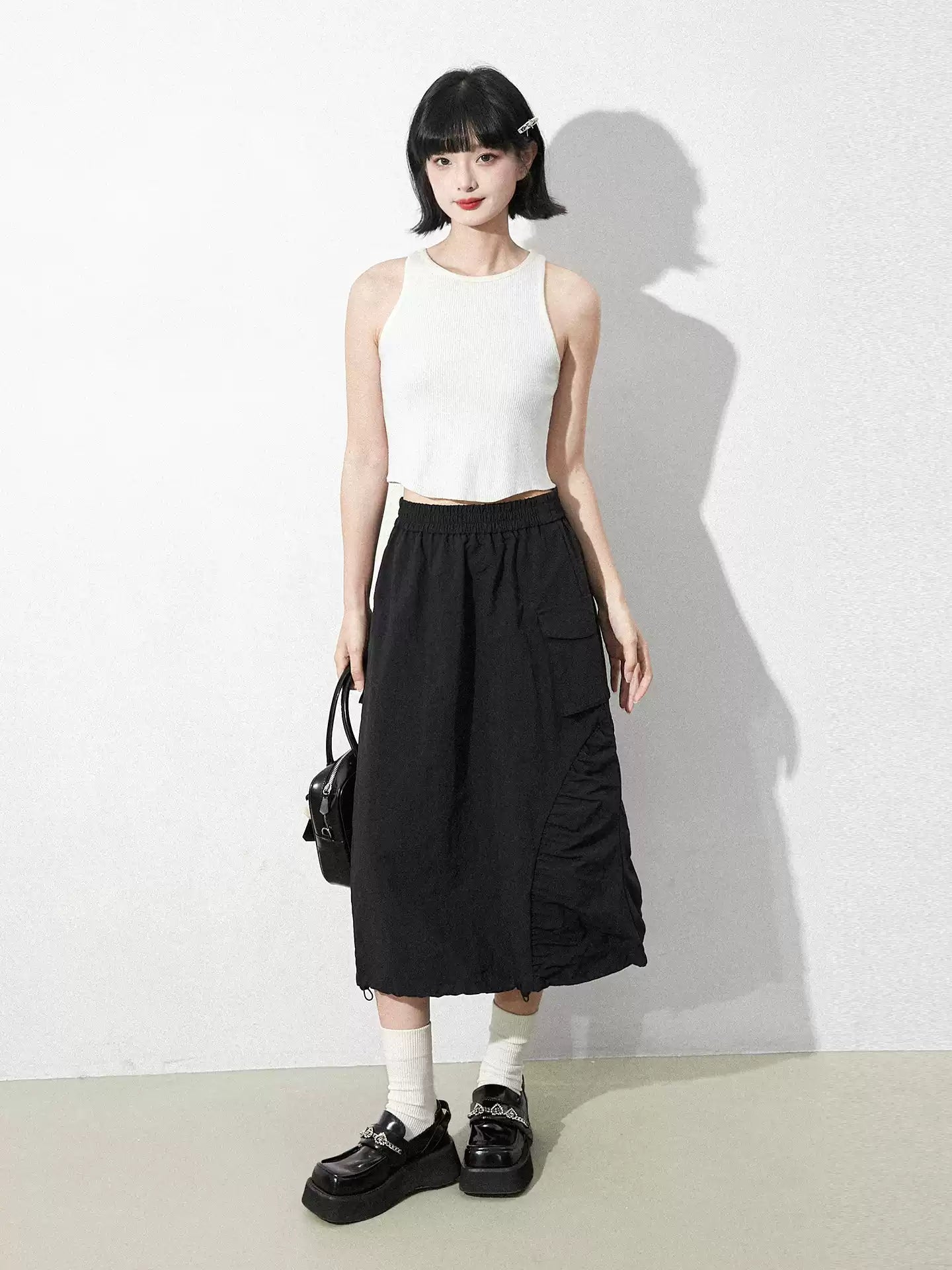 This skirt blends edgy charm with playful sweetness through its functional drawstring detail and sharp A-line silhouette. The adjustable waist and strategic pleating create a flattering, customized fit. Designed in versatile black, it balances minimalist structure with youthful rebellion, offering a statement piece that effortlessly transitions from casual daytime wear to bold nighttime street style.