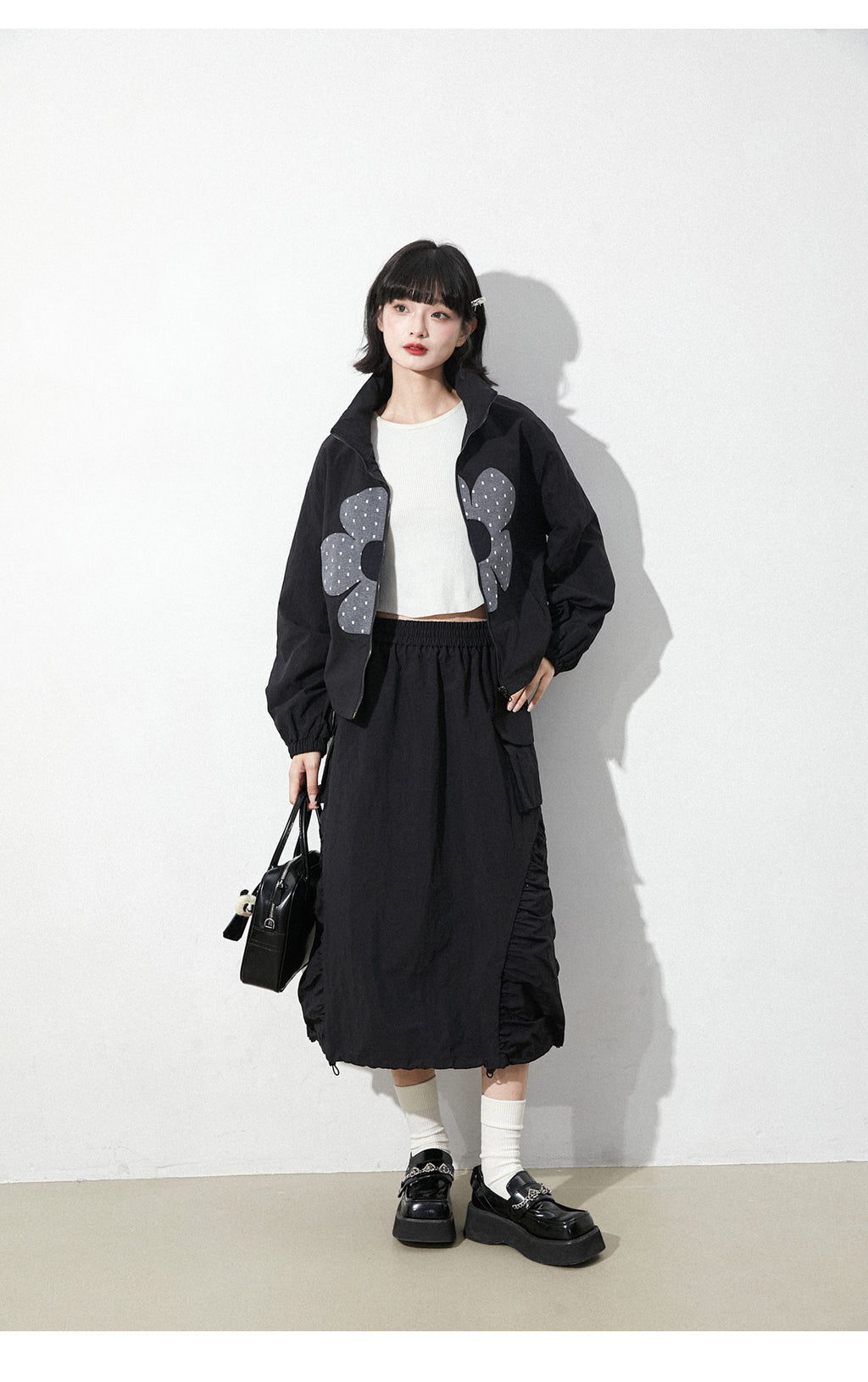 This skirt blends edgy charm with playful sweetness through its functional drawstring detail and sharp A-line silhouette. The adjustable waist and strategic pleating create a flattering, customized fit. Designed in versatile black, it balances minimalist structure with youthful rebellion, offering a statement piece that effortlessly transitions from casual daytime wear to bold nighttime street style.