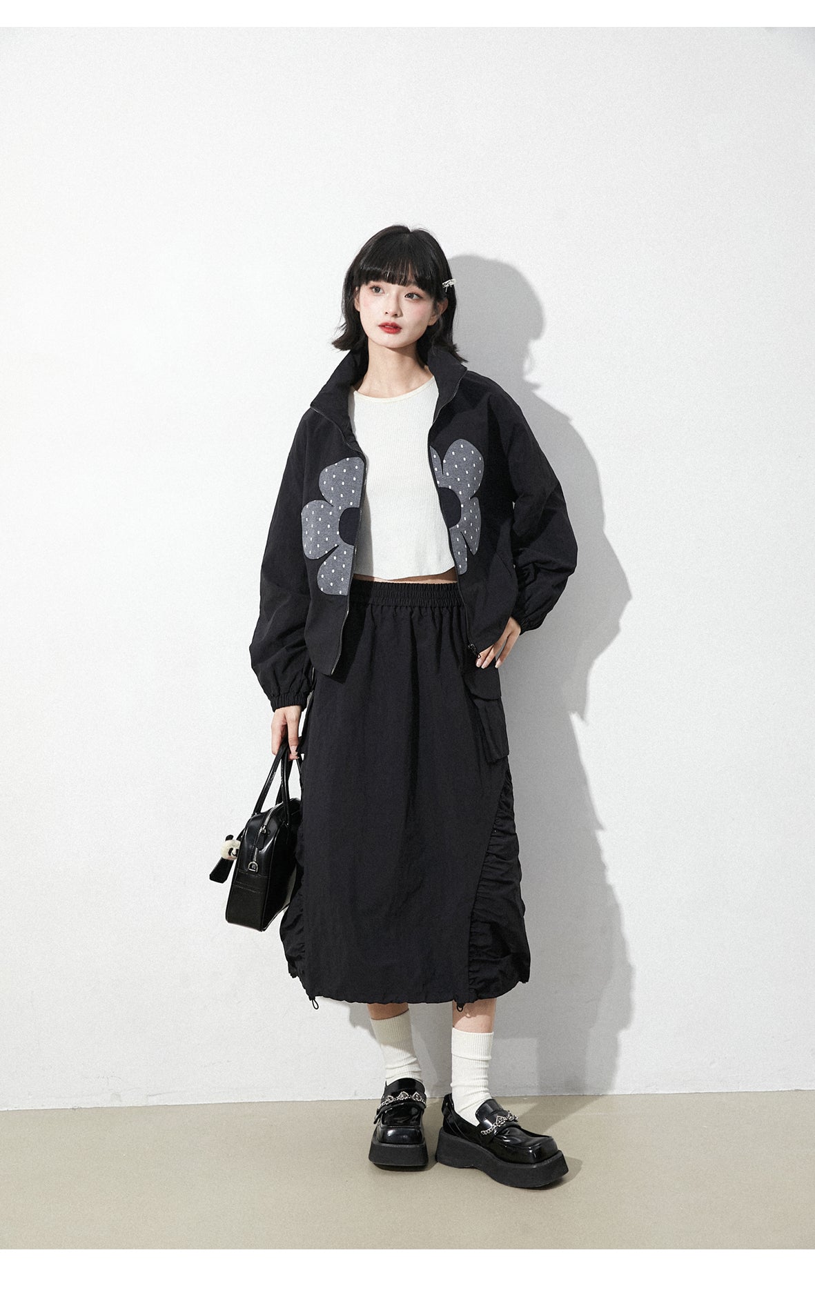 This skirt blends edgy charm with playful sweetness through its functional drawstring detail and sharp A-line silhouette. The adjustable waist and strategic pleating create a flattering, customized fit. Designed in versatile black, it balances minimalist structure with youthful rebellion, offering a statement piece that effortlessly transitions from casual daytime wear to bold nighttime street style.