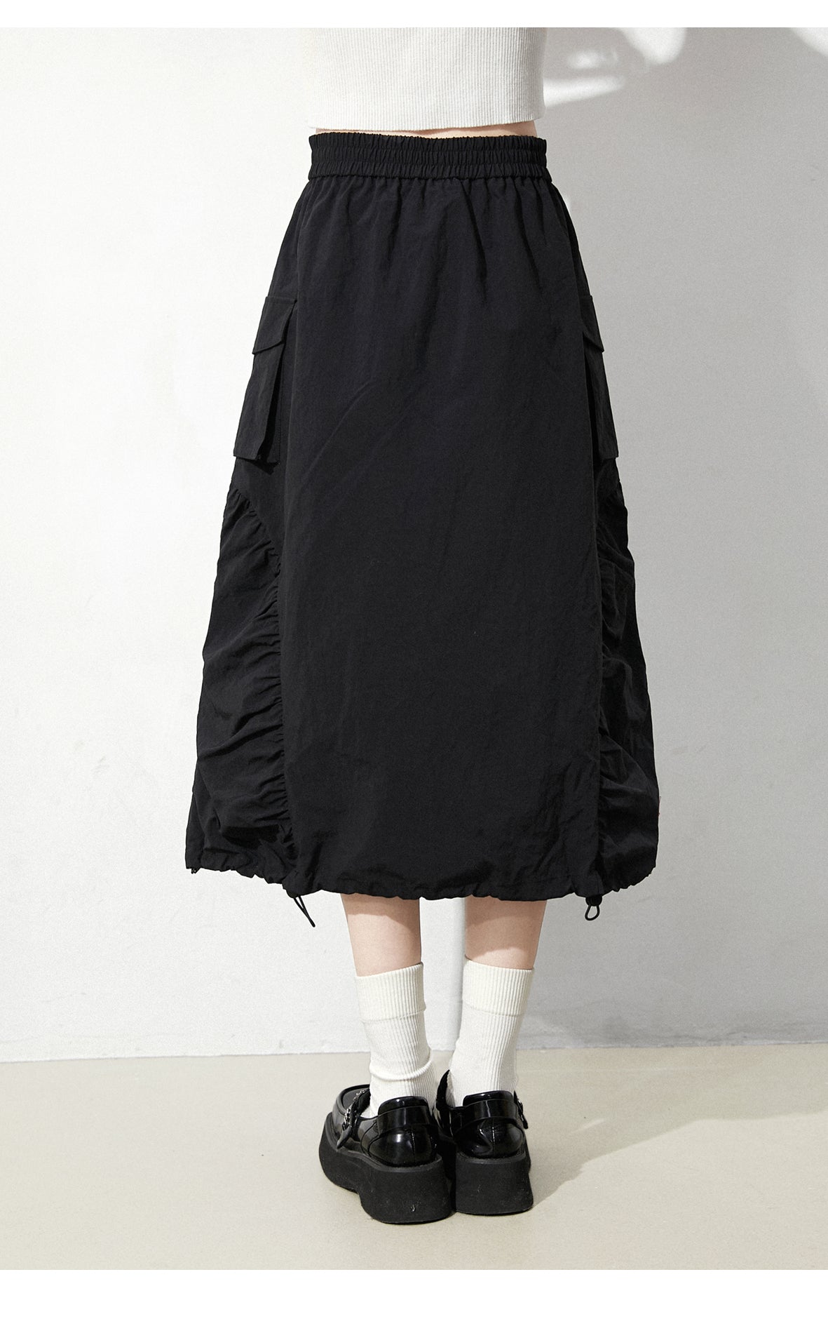 This skirt blends edgy charm with playful sweetness through its functional drawstring detail and sharp A-line silhouette. The adjustable waist and strategic pleating create a flattering, customized fit. Designed in versatile black, it balances minimalist structure with youthful rebellion, offering a statement piece that effortlessly transitions from casual daytime wear to bold nighttime street style.