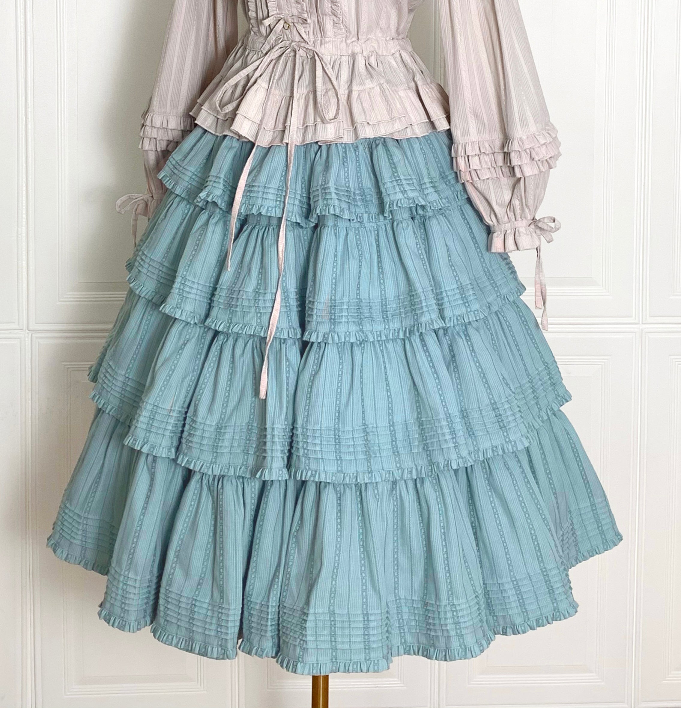 Embrace rustic charm with this Heidi-inspired cottagecore Lolita skirt, crafted from premium heavy cotton for structured elegance. Meticulous embroidery and delicate trims adorn its flowing silhouette, echoing the whimsy of alpine meadows and storybook dreams. Designed for layering or standalone wear, this skirt offers versatility and timeless appeal. Available in multiple nature-inspired hues, it effortlessly complements blouses or JSKs for a pastoral yet polished coordinate. Perfect for tea parties, garde