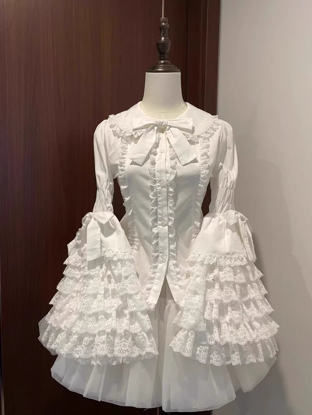 Inspired by antique porcelain dolls and Victorian elegance, this blouse features dramatic gigot sleeves, delicate lace trim, and a tailored yet forgiving fit. The ivory and black color options evoke timeless sophistication, while lightweight fabric ensures comfort. Designed to layer under jumperskirts or wear standalone, it celebrates opulent nostalgia with modern inclusivity. Perfect for creating a poetic, romantic silhouette.