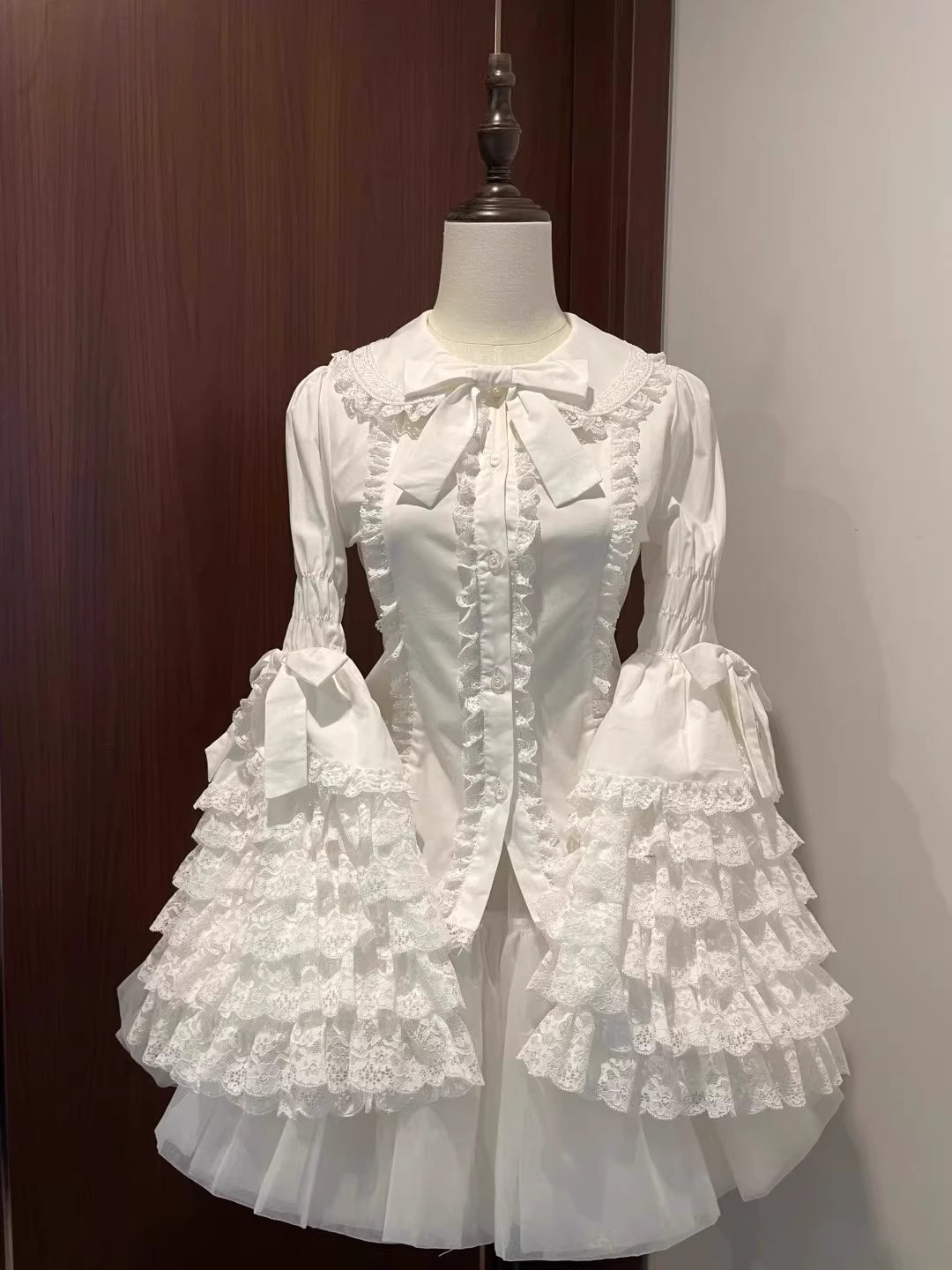 Inspired by antique porcelain dolls and Victorian elegance, this blouse features dramatic gigot sleeves, delicate lace trim, and a tailored yet forgiving fit. The ivory and black color options evoke timeless sophistication, while lightweight fabric ensures comfort. Designed to layer under jumperskirts or wear standalone, it celebrates opulent nostalgia with modern inclusivity. Perfect for creating a poetic, romantic silhouette.