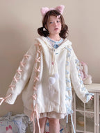 Inspired by fairy-tale whimsy, this hooded cardigan features soft bunny ear details and a playful tie-front design. Crafted from plush, cozy knit, it combines adorable charm with practical warmth for autumn and winter. The creamy white hue and rounded silhouette evoke a sugary sweetness, perfect for layering over dresses or pairing with skirts—a delightful blend of childhood nostalgia and wearable comfort.