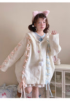 Inspired by fairy-tale whimsy, this hooded cardigan features soft bunny ear details and a playful tie-front design. Crafted from plush, cozy knit, it combines adorable charm with practical warmth for autumn and winter. The creamy white hue and rounded silhouette evoke a sugary sweetness, perfect for layering over dresses or pairing with skirts—a delightful blend of childhood nostalgia and wearable comfort.