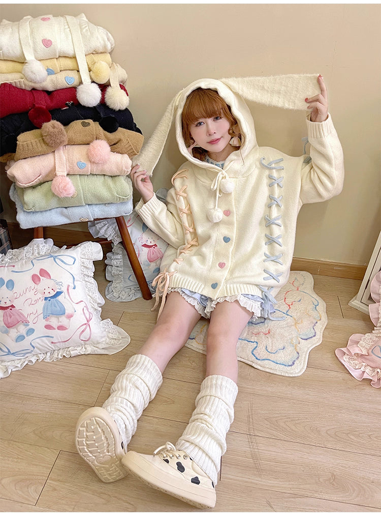 Inspired by fairy-tale whimsy, this hooded cardigan features soft bunny ear details and a playful tie-front design. Crafted from plush, cozy knit, it combines adorable charm with practical warmth for autumn and winter. The creamy white hue and rounded silhouette evoke a sugary sweetness, perfect for layering over dresses or pairing with skirts—a delightful blend of childhood nostalgia and wearable comfort.