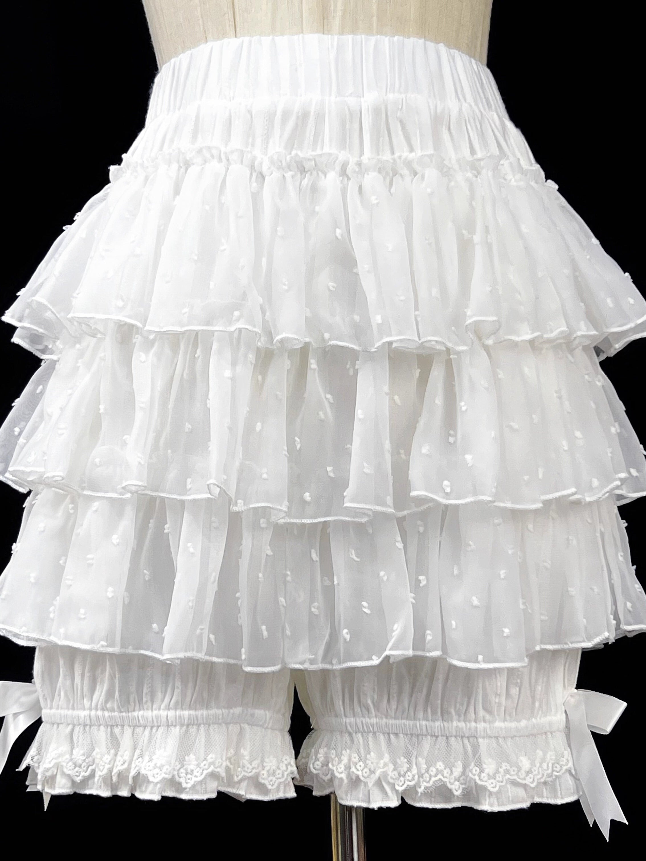 These delicate safety shorts combine functionality with Lolita aesthetics. Featuring lace-trimmed tiers and a bloomer-inspired design, they provide discreet coverage under skirts and dresses. Rendered in classic black and white, the lightweight fabric ensures comfort while adding a romantic touch to any coordination. Perfect for both sweet and Gothic styles, they offer practical elegance for dynamic wear.