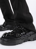 Black glossy sneakers worn with black pants on a white background